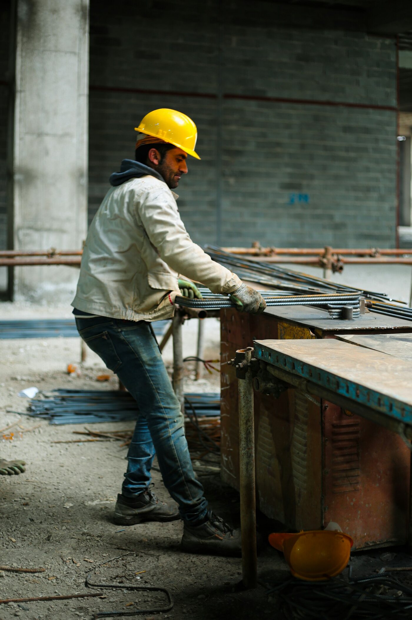 Trabalhador de capacete em obra, manuseando vergalhões